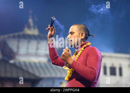 Ein hinduistischer Priester führt Aarati auf, während er Gott Shiva während des Maha Shivaratri Festivals im Pashupatinath Tempel betet. Hinduistische Anhänger aus Nepal und Indien kommen in diesen Tempel, um am Shivaratri-Festival teilzunehmen, einem der größten hinduistischen Feste, die Lord Shiva gewidmet sind und von Anhängern auf der ganzen Welt gefeiert werden. Stockfoto