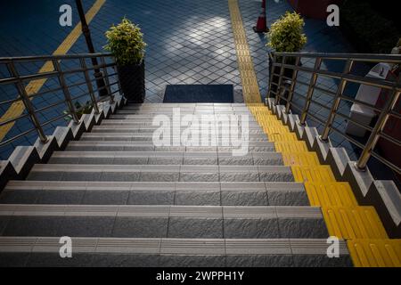 Treppe mit gelbem taktilem Pflaster, strukturierter Gehweg für Blinde. Stockfoto