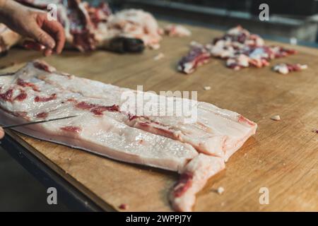 Ein Metzger schneidet Schweinefleisch auf dem Holztisch und bereitet Schweinefleisch zu. Hochwertige Fotos Stockfoto