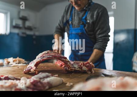 Schweinefleisch verarbeiten, ein alter Metzger, der im Laden arbeitet, natürliches Fleisch. Hochwertige Fotos Stockfoto