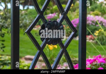 Blumengarten hinter einem schmiedeeisernen Spalier in Panola Valley Gardens, einem Veranstaltungsort für Hochzeiten in Lindstrom, Minnesota, USA. Stockfoto