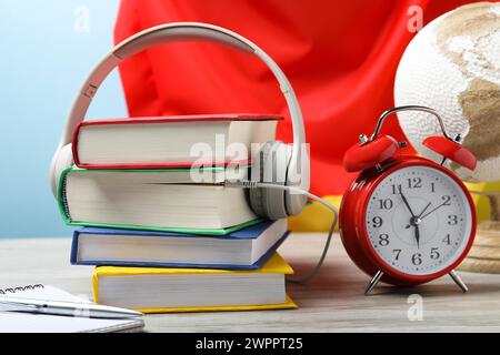 Fremdsprachenlernen. Verschiedene Bücher, Kopfhörer, Wecker und Schreibwaren auf Holztisch in der Nähe der Flagge Deutschlands Stockfoto