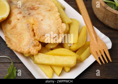 Leckerer Fisch und Chips serviert auf Holztisch, Nahaufnahme Stockfoto