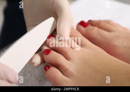 Pedikurist, der die Zehennägel des Kunden im Schönheitssalon ablegt, Nahaufnahme Stockfoto