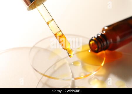 Tropfendes feuchtigkeitsspendendes Serum von Pipette auf beigem Hintergrund, Nahaufnahme Stockfoto