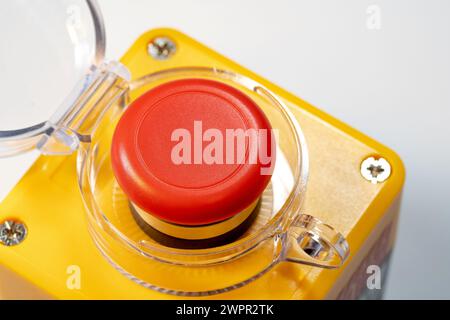 Detaillierte Nahaufnahme eines roten Not-aus-Schalters für Industriemaschinen, eines roten gelben Panikschalters mit geöffneter Abdeckung. Hohe Beanspruchung Stockfoto