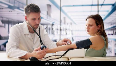 Männlicher Arzt prüfen schwangere Frau Blutdruck im Krankenhaus Stockfoto