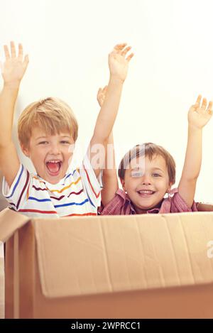 Box, Kinder oder Porträt von Geschwistern, die im Haus spielen, um Spaß zu haben, sich zu binden oder Hände hoch zu spielen. Pappe, Lernen und begeisterte Kinder im Wohnzimmer für Stockfoto