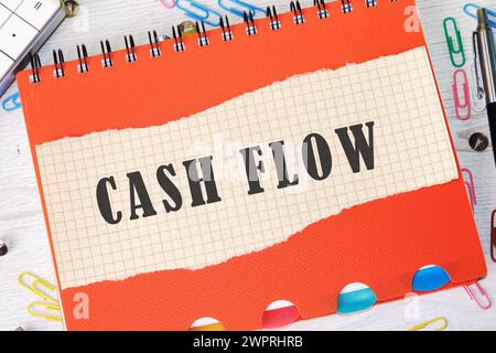 Cashflow-Text auf einem Blatt Papier in einem Käfig auf dem Hintergrund eines orangen Notizbucheintrags Stockfoto