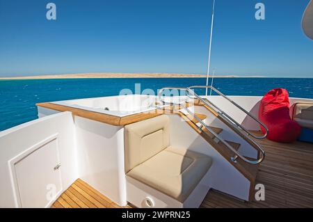 Teakholzdeck einer großen Luxus-Motoryacht mit Whirlpool und tropischem Meerblick im Hintergrund Stockfoto