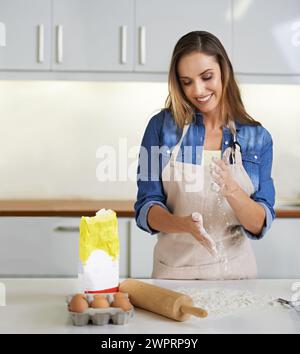 Glückliche Frau, die in der Küche zuhause mit Mehl, Teig oder einem Lächeln die Hände backen und klatschen kann. Kochen, Weizen und Person mit Staub für Gebäck Stockfoto