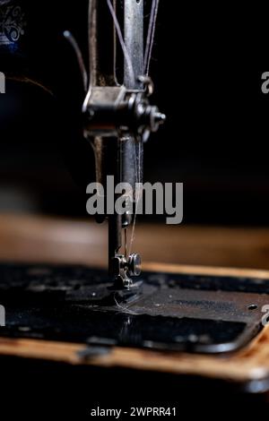 Eine alte Nähmaschine steht zu Hause auf dem Tisch, bereit zum Arbeiten und Nähen. Manuelle Nähmaschine im klassischen Retro-Stil, bereit für Näharbeiten. Die Maschine Stockfoto