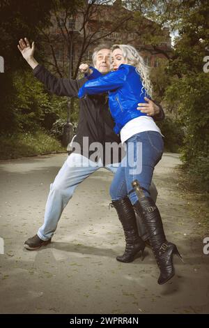 Hübsche junge Frau, die von einem älteren Mann im Park verfolgt und angegriffen wird Stockfoto