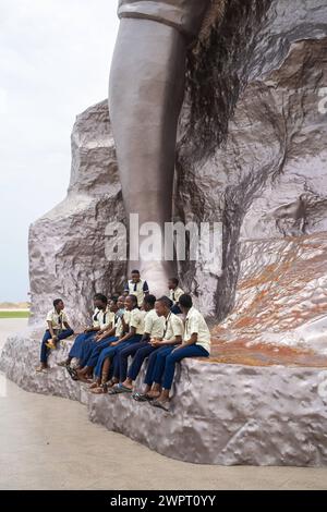 Monument Amazone Benin, Cotonou März 2024: Seit mitte 2022 steht das neue 30 Meter hohe Wahrzeichen der westafrikanischen Staat Benin. Die Amazone soll an die historische, rein weibliche Militäreinheit der Agojie auch Dahomey-Amazonen erinnern. Schuljugendlichen sitzen am Fusse der Statur. *** Monument Amazonas Benin, Cotonou März 2024 das neue 30 Meter hohe Wahrzeichen des westafrikanischen Staates Benin steht seit Mitte 2022 der Amazonas soll an die historische, weibliche Militäreinheit der Agojie erinnern, auch bekannt als die Dahomey Amazonen-Schulkinder, die am Fuße des Th sitzen Stockfoto