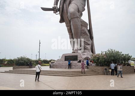 Monument Amazone Benin, Cotonou März 2024: Seit mitte 2022 steht das neue 30 Meter hohe Wahrzeichen der westafrikanischen Staat Benin. Die Amazone soll an die historische, rein weibliche Militäreinheit der Agojie auch Dahomey-Amazonen erinnern. Touristen schauen sich das Denkmal an. Auf die Tafel zu lesen: Symbole de notre amour et de notre Engagement pour le Pays, nos amazones ont su, par leur bravoure, autant que les hommes, dÃ fendre la patrie. Telles nos amazones, la femme BÃ ninoise EST notre fiertÃ . Patrice Talon, 2022 Google übersetzung: Als Symbol unserer Liebe und unseres Engagements Stockfoto