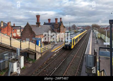 Merseyrail Stadler Baureihe 777 Elektrozug 777006 am Bahnhof Ellesmere Port in Cheshire, Großbritannien mit den Bahnhofsgebäuden Stockfoto