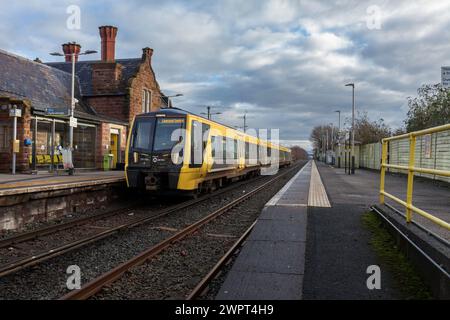 Merseyrail Stadler Baureihe 777 Elektrozug 777006 am Bahnhof Ellesmere Port in Cheshire, Großbritannien mit den Bahnhofsgebäuden Stockfoto