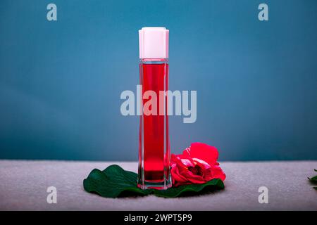 Rote Flasche mit Damenparfüm auf rosa blauem Hintergrund Stockfoto