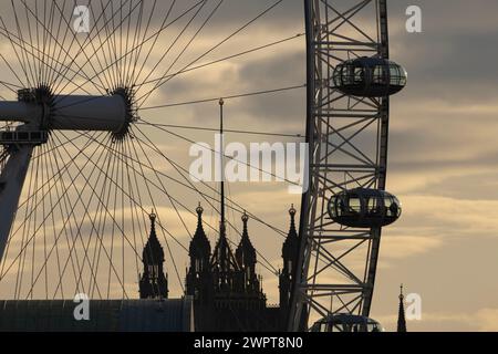 London Eye oder Millennium Wheel Touristenbeobachtungsrad Nahaufnahme von Schoten und Speichen bei Sonnenuntergang mit den Houses of Parliament im Hintergrund, City Stockfoto