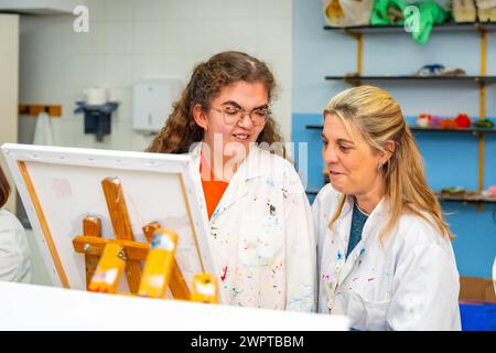 Behinderte Frau und Lehrerin, die in einem Malkurs auf Leinwand steht Stockfoto