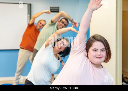 Konzentrieren Sie sich auf eine Frau mit Down-Syndrom und eine Gruppe von Menschen mit besonderen Bedürfnissen, die sich im Fitnessstudio dehnen Stockfoto