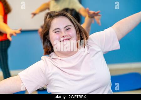 Frau mit Down-Syndrom lächelt in die Kamera, während sie im Fitnessstudio trainiert Stockfoto