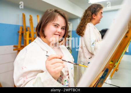 Porträt einer Frau mit Down-Syndrom in einer Malklasse, die in die Kamera lächelt Stockfoto