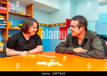 Frau mit Down-Syndrom und behinderter Mann, der Brettspiele in einem Tageszentrum spielt Stockfoto