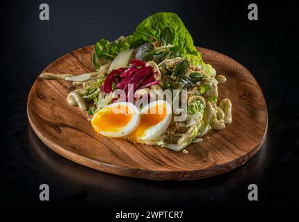 Salat auf Holzteller mit weich gekochtem Ei Stockfoto