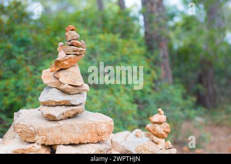 Sorgfältig gestapelte, leicht rote Steine bilden eine Steinfigur, Steinhügel, Wegmarke, Markierung im Wald, Wanderweg von Sant Elm zum alten Wachturm Stockfoto