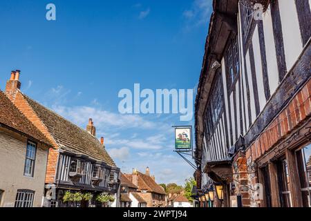 Das schwarz-weiße, aus Fachwerk gefertigte George Inn and Pub Schild in der High Street, Alfriston, einem hübschen historischen Dorf im Wealden District in East Sussex Stockfoto