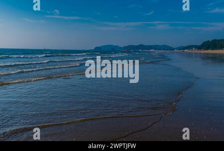 Sanfte Wellen sprudeln über den Sandstrand mit klarem blauen Himmel in Südkorea Stockfoto