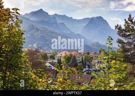 Wettersteingebirge mit Alpspitze, Zugspitzmassiv und Häusern im Stadtteil Partenkirchen vom Philosenweg aus gesehen, Herbst, Hinterleuchtung Stockfoto