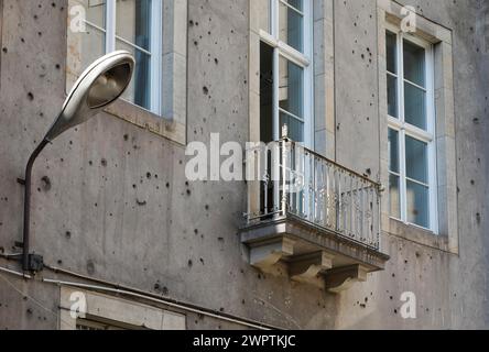 Zeitgeschichte auf einem Gebäude in Berlin Mitte. Eine Laterne aus der DDR-Zeit auf einem Gebäude, das deutlich sichtbare Spuren der Zweiten Welt zeigt Stockfoto