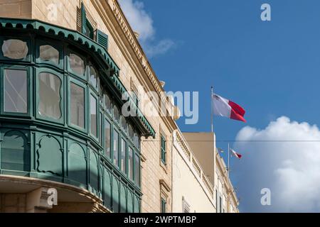 Eine grüne Gallarija, ein typisches Element der maltesischen Volksarchitektur, mit maltesischen Fahnen, die im Wind wehen, Valletta, Malta Stockfoto