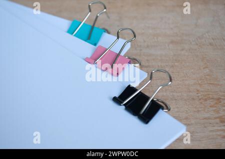 Leere Dokumentenpapiere mit farbigen Büroklammern pastellfarben auf Holztisch. Stockfoto