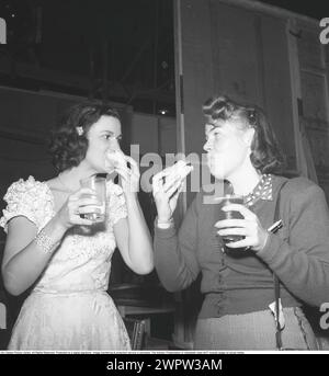 Eine schnelle Mahlzeit 1943. Zwei Frauen sahen, wie sie etwas eilig aßen und trinken, während sie ihre Sandwiches und Getränke im Stehen beendeten. 1943. Kristoffersson Ref. E106-6 Stockfoto