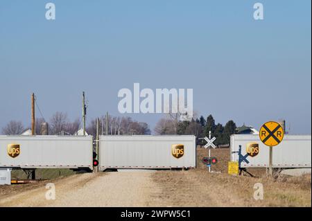 Waterman, Illinois, USA. Ein intermodaler Güterzug brüllt durch einen unbefestigten Straßenübergang, während er westwärts durch das ländliche Illinois fährt. Stockfoto