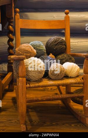 Kugeln aus Kitting Garn auf alten Miniatur gewebten Sitz Holz Schaukelstuhl im Gästezimmer im Blockhaus Haus. Stockfoto