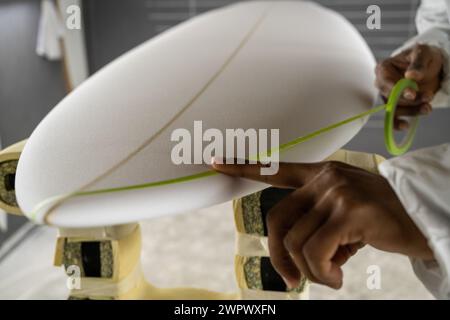 Surfboard-Herstellung, Shaper an Bord Details. Begriff der industriellen Fertigung, qualifizierter Beruf, Beruf und Beschäftigung. Stockfoto