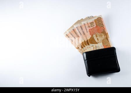 5000 5000 Rupien Banknoten, die mit einer schwarzen Ledergeldbörse ausgerichtet sind. Pakistan State Bank offizielle Geldscheine 2024 isoliert auf weißem Hintergrund. Stockfoto