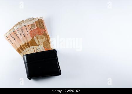 5000 5000 Rupien Banknoten, die mit einer schwarzen Ledergeldbörse ausgerichtet sind. Pakistan State Bank offizielle Geldscheine 2024 isoliert auf weißem Hintergrund. Stockfoto