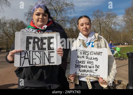 London, Großbritannien. März 2024. Zwei Personen halten an einem sonnigen Tag Protestzeichen in einem Londoner Park. Ein Schild heißt „FREIES PALÄSTINA“, das andere bezieht sich auf Aaron Bushnell und kritisiert die politische Normalisierung. Im Hintergrund sind baumlose Bäume, Fußgänger und ein grünes Fahrrad zu sehen. Tausende von Menschen versammeln sich in der Hyde Park Corner und marschieren dann zur amerikanischen Botschaft, um einen Waffenstillstand in Gaza zu fordern. Penelope Barritt/Alamy Live News Stockfoto