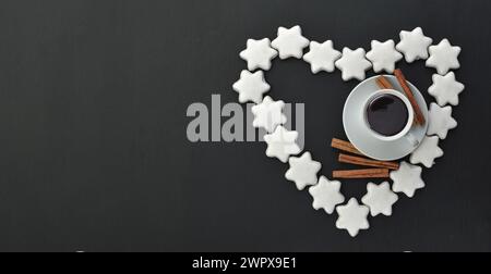 Weiße Tasse und Untertasse Espresso-Kaffee auf einem Hintergrund aus verstreuten glasierten Lebkuchen, Zimtstangen und Gewürzen. Duftender Snack. Flache Lage, oben VI Stockfoto