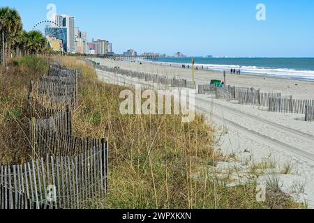 Sandzaun im Zickzackmuster auf Dünen mit entferntem Stadtbild am Myrtle Beach Stockfoto