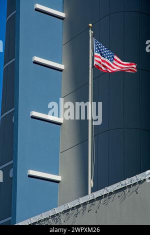 Amerikanische Flagge mit Sonnenlicht auf dem Mast, die vor dem Hochhaus steht Stockfoto
