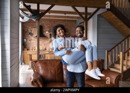 Afrikanischer liebender Ehemann, der die geliebte lächelnde Frau hält Stockfoto