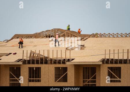 Dachreparatur auf dem Dach Bauarbeiter installieren neues Dach. Bauarbeiter, die eine große Dachwohnung überdacht haben. Dachdecker Stockfoto