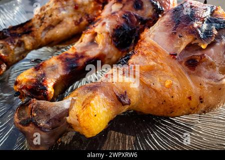 Genießen Sie den köstlichen Anblick der saftigen, frisch gegrillten Hähnchenschenkel, die auf einer Glasplatte wunderschön präsentiert werden und Sie einladen, jeden fla zu genießen Stockfoto