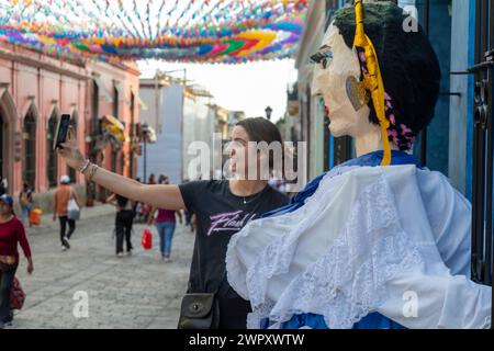 Oaxaca, Mexiko - Ein Tourist macht ein Selfie mit einer riesigen Pappmaché-Puppe auf der Alcala, einer Fußgängerzone. Stockfoto